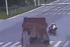 道路端から一気に道路を横断しようとしたバイクがトラックに轢かれる