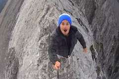 両端が切り立った断崖絶壁の山の尾根を自撮りしながら歩く男性