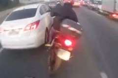 渋滞の車列の間を走行していたバイクが車と接触し転倒