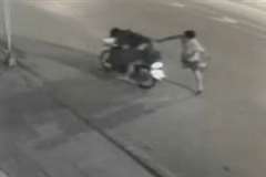 道路を走行する3人乗りのバイクにマチェーテを振り下ろす男