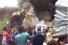 事故を起こしたトラックから積荷を強奪する人々