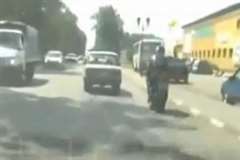 車に幅寄せされ転倒し街路灯の鉄柱に激突するライダー